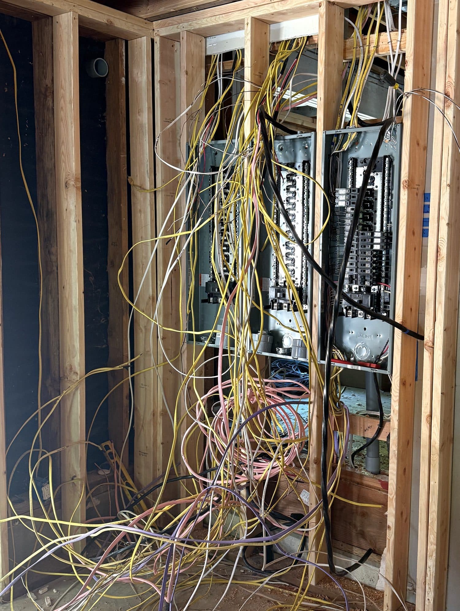 A wall opened up mid-job, with dozens of circuit wires pulled out between the studs.